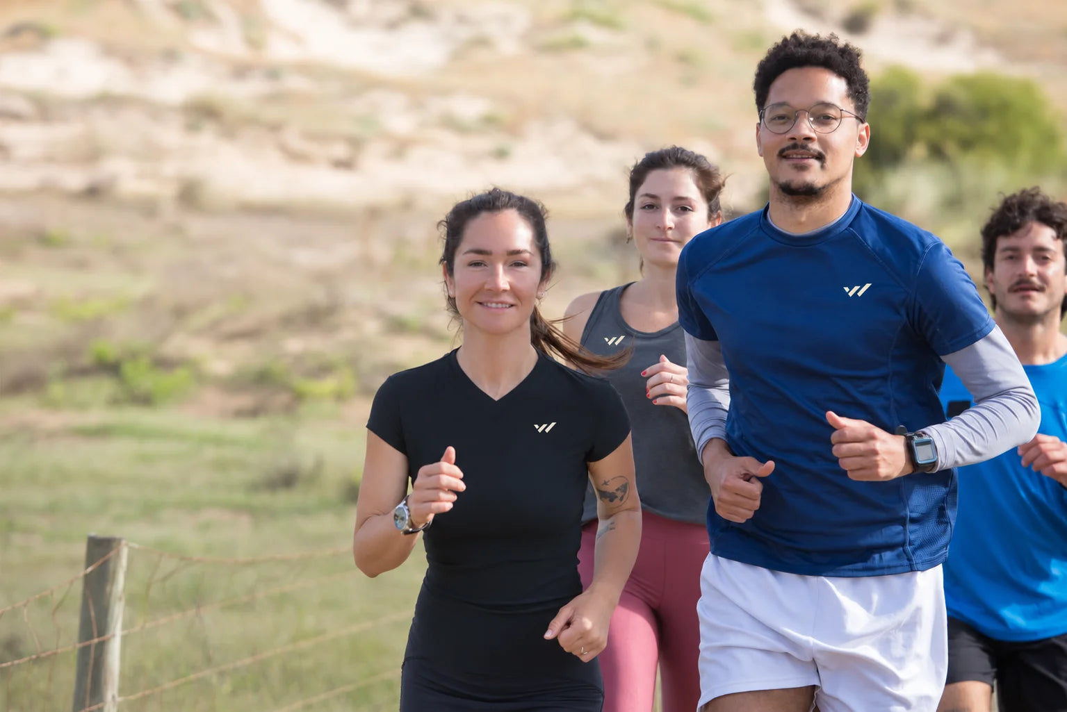 A diverse group of four athletes running together in Willpower apparel